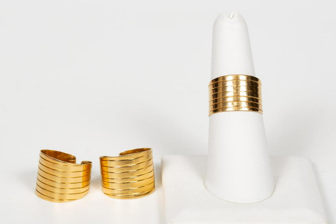 MODERN 3PC 18K YELLOW GOLD RING & EARRING SET: A modern three piece 18k yellow gold ear cuff and ring set having wide bands with parallel line motif. Marked 18k, JJ, and Y. Multi size ring with open back and scroll ends to ear cuffs. Approx. 0.50"