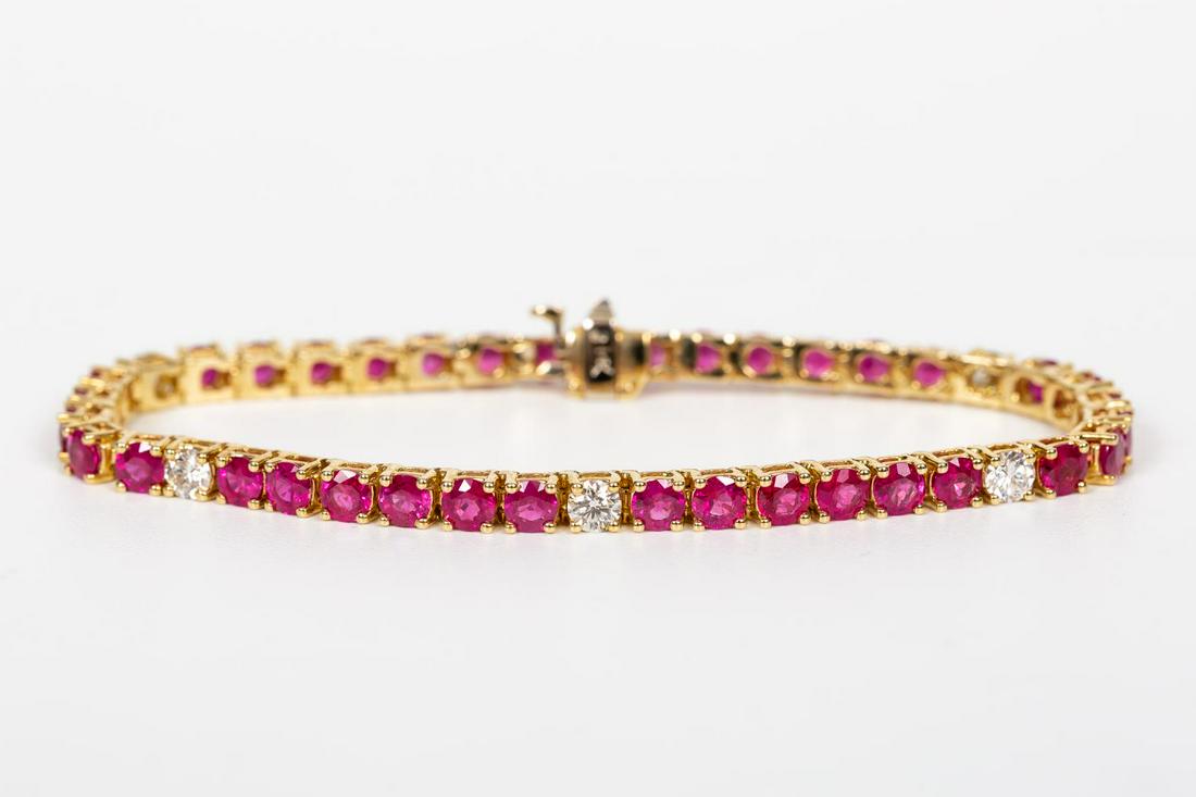 14K GOLD, RUBY & DIAMOND TENNIS BRACELET: A 14k yellow gold, ruby, and diamond line bracelet comprising of thirty-six round brilliant cut rubies (9.36 ctw, color: medium dark strong red, clarity: eye clean) and six round brilliant cut diamond