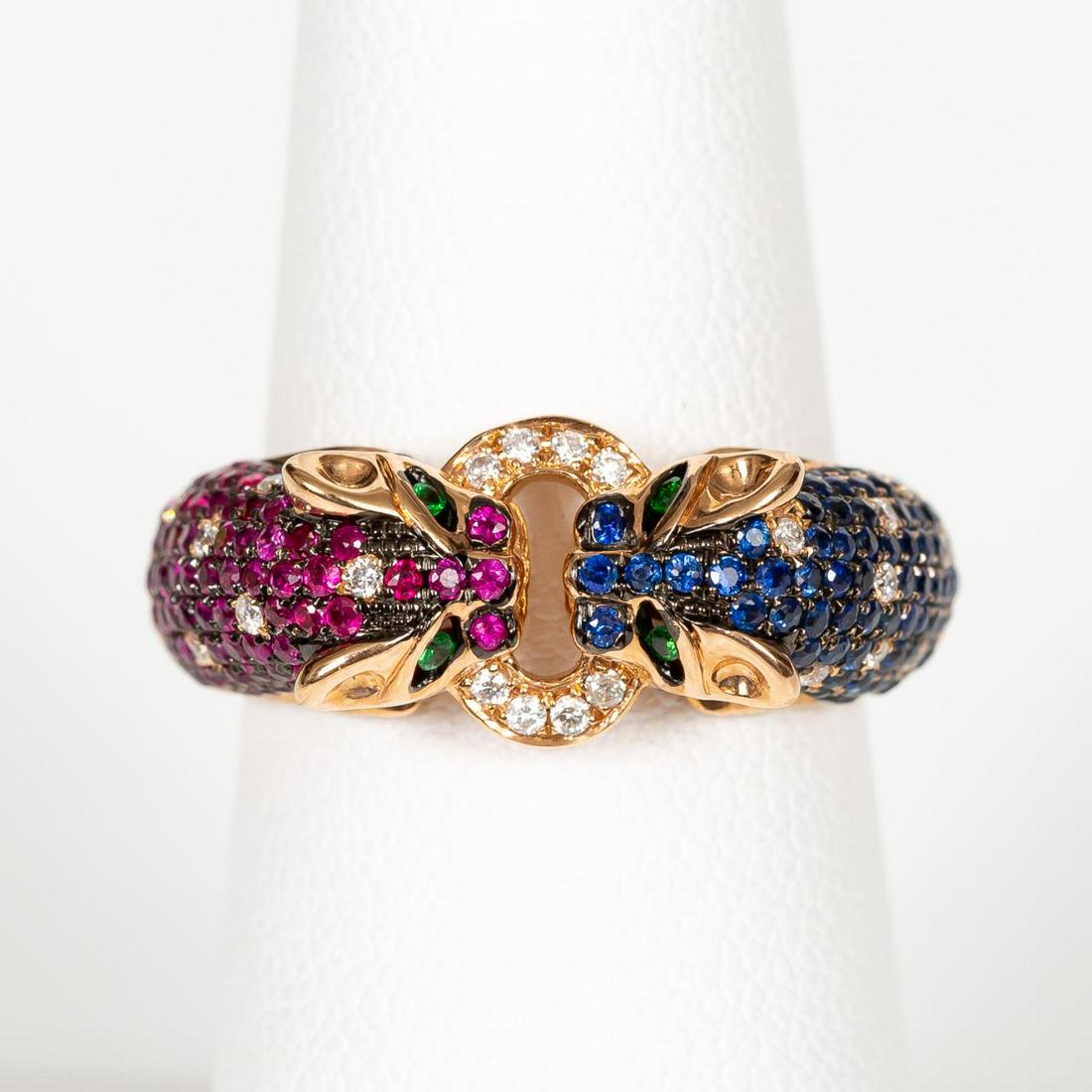 18K GOLD MULTI-STONE "DOUBLE PANTHER" RING: A 18k yellow gold and multi-gemstone double leopard form ring comprising of round cut rubies (0.50 ctw), round cut blue sapphires (.048 ctw), and round cut diamonds (0.14 ctw). Marked on interior 18K