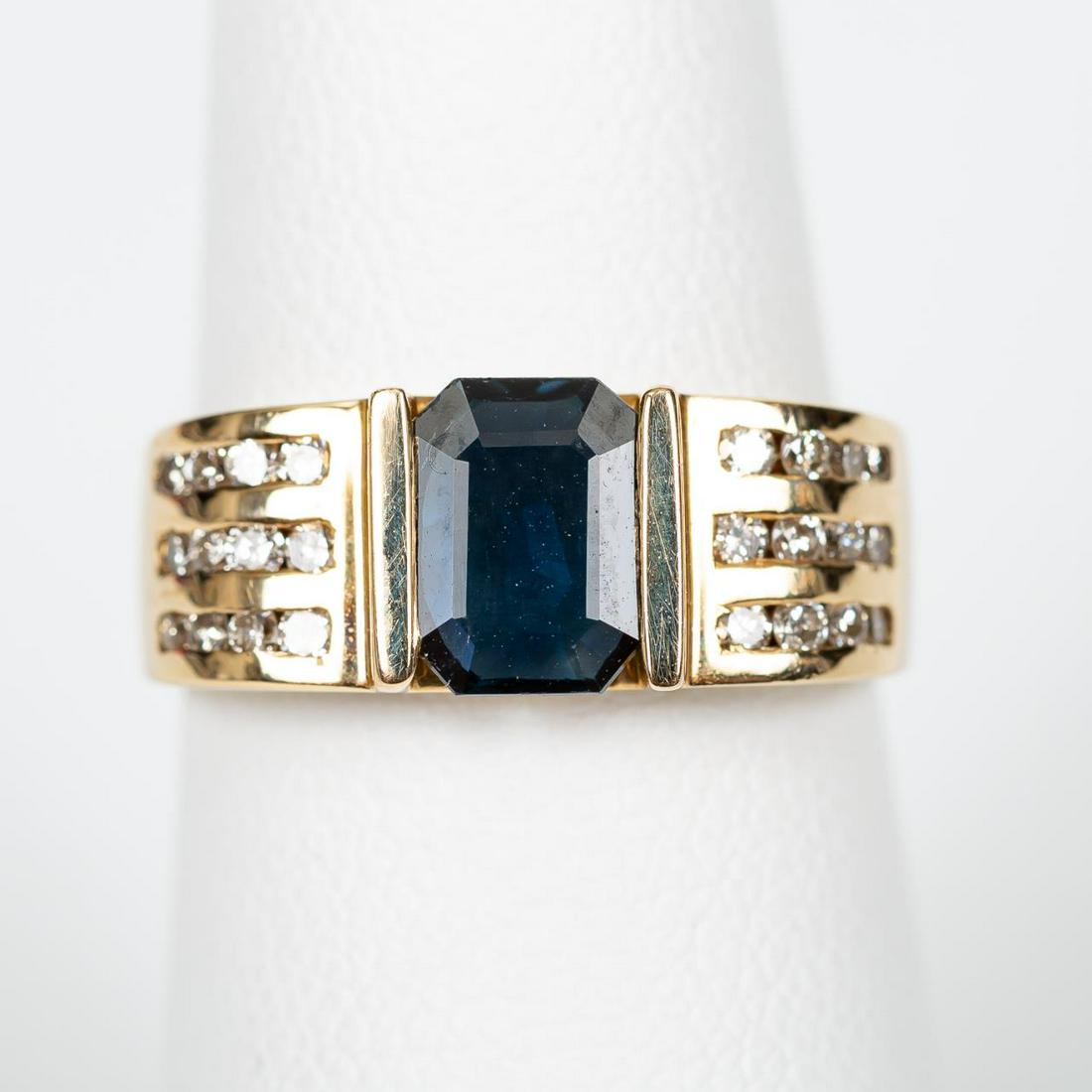 14K YELLOW GOLD, SAPPHIRE & DIAMOND RING: A 14K yellow gold ring with central 0.88 carat emerald cut blue sapphire flanked by three rows of twenty-four diamonds totaling 0.30 carats. Marked “LCI, 14K”. Approx: 6 (size); with a total appro