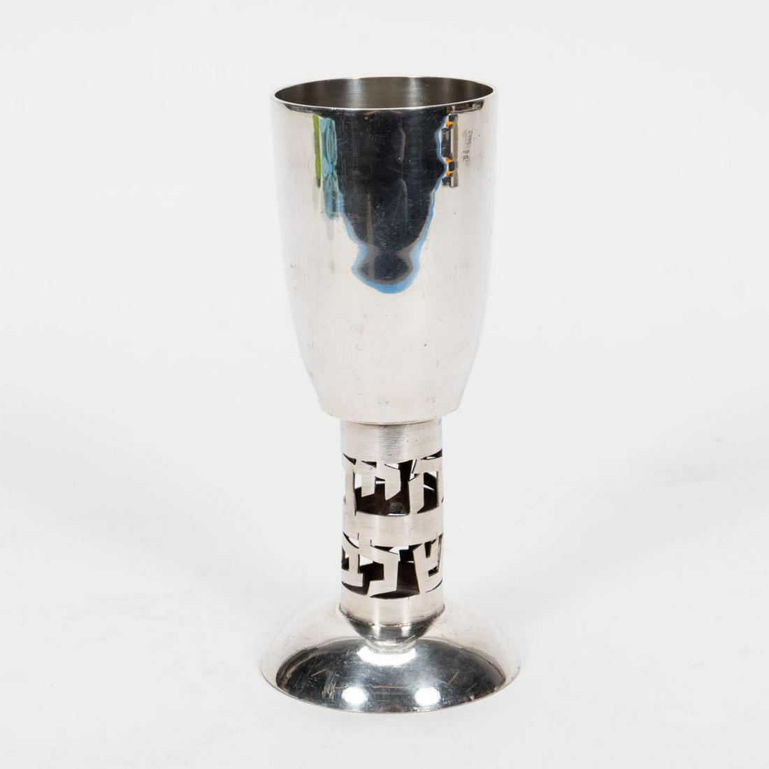 ISAAC BIER, STERLING SILVER CEREMONIAL KIDDUSH CUP: Isaac Bier (Israeli, 20th century). A sterling silver kiddush cup with hand cut Hebrew letters across the stem. Marked to underside "Made In Isreal, Bier Sterling". Approx: h. 7.25", w. 3.25"; with a 