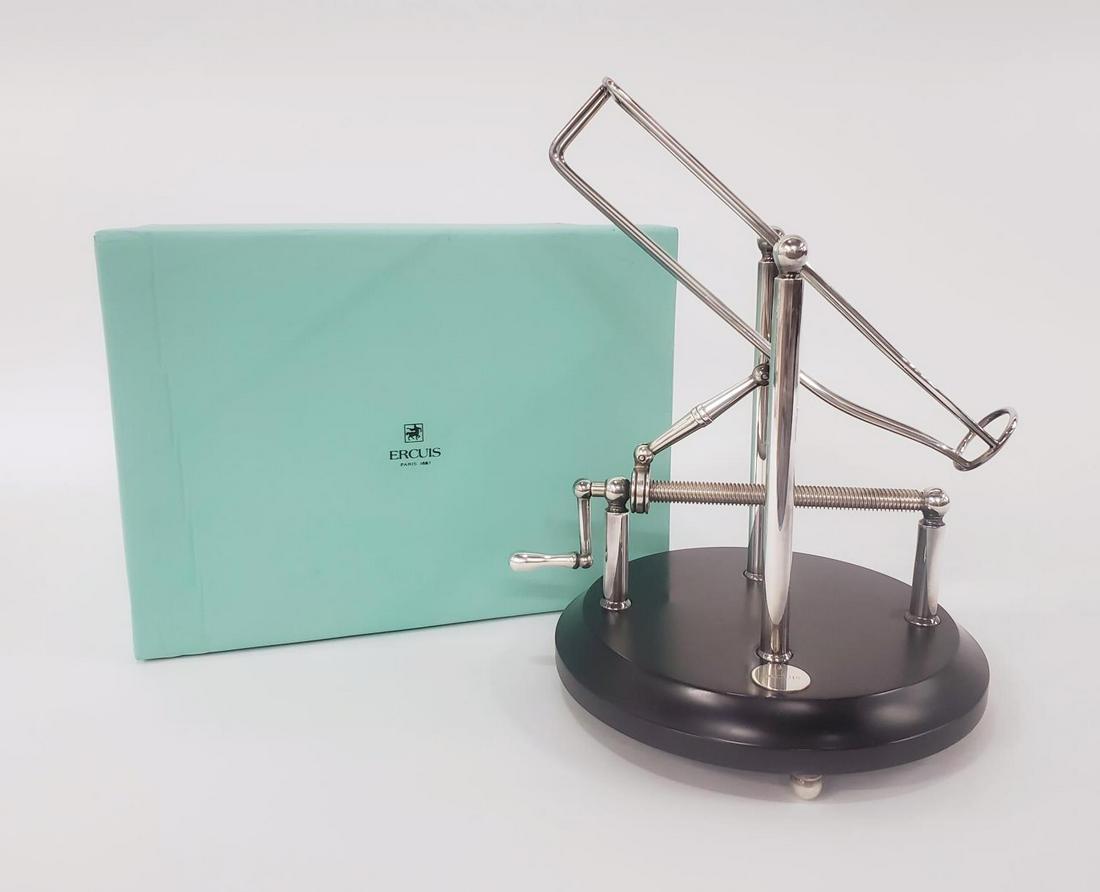 ERCUIS MODERN SILVERPLATED WINE BOTTLE HOLDER: Ercuis (French, founded 1867), 20th century. A silverplated wine bottle holder with built in crank accompanied by the original box. Marked "Ercuis" to base. Approx: h. 10.75", w. 11.5", d. 9.25" (flat