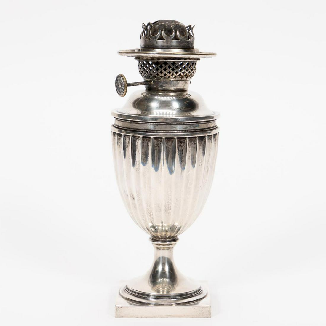 ENGLISH EDWARD VII STERLING SILVER OIL LAMP, 1902: The Goldsmiths and Silversmiths Co. Ltd., (English, 1880-1952). Edwardian era sterling silver oil lamp in the regency taste having a pierced burner, fluted font, socle plinth and resting on a square w