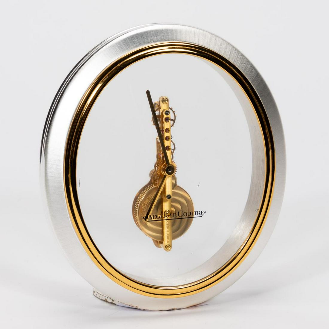 JAEGER LECOULTRE, MID CENTURY SKELETON CLOCK: Jaeger LeCoultre (Swiss, founded 1833). A silver and gold plated desk clock with clear skeleton view featuring an 8 day power reserve, 16 jewel mechanical movement; circa 1965. Marked to glass "Jaeger