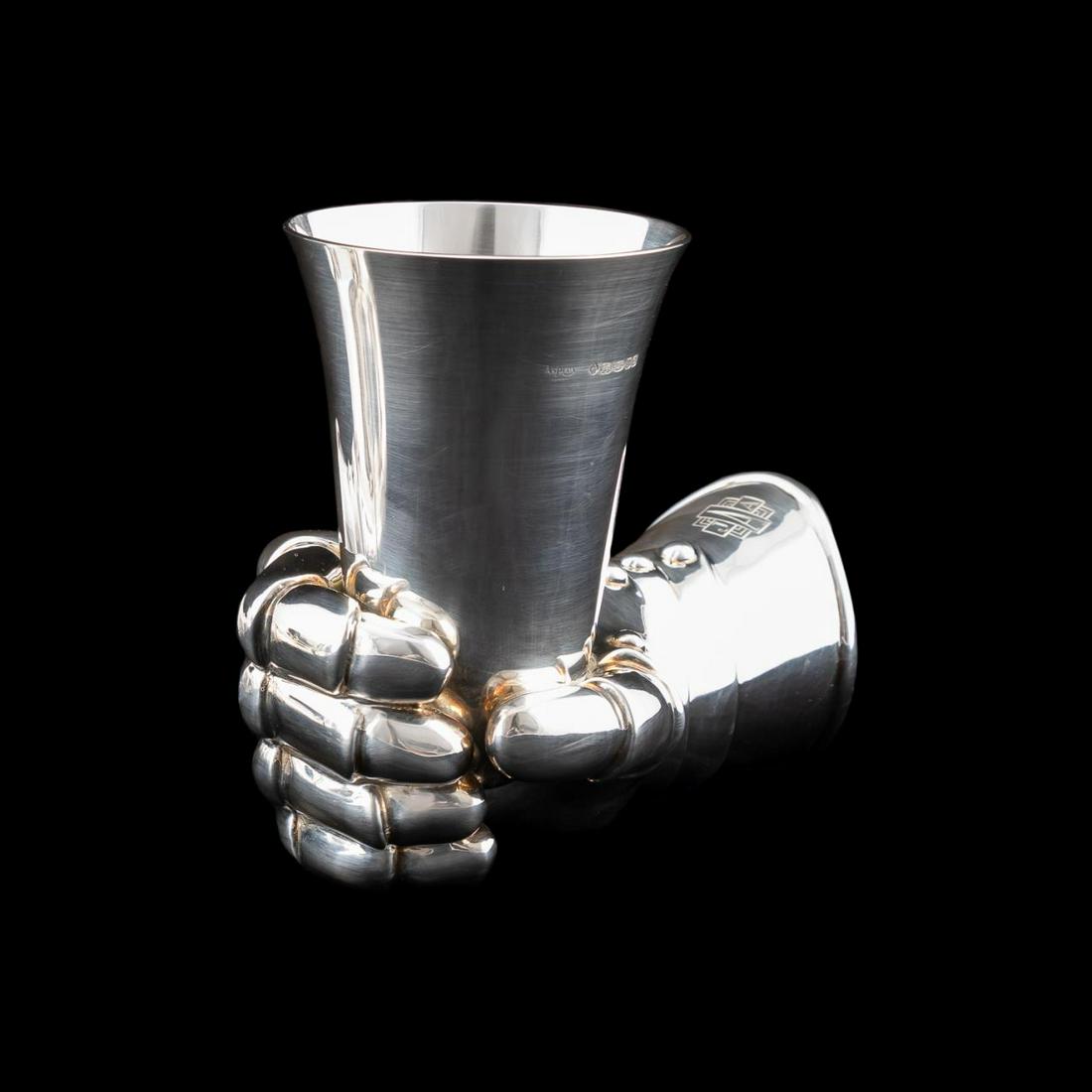 ASPREY STERLING SILVER "KNIGHT'S HAND" VASE, 2004: Asprey, 2004. Elizabeth II English sterling silver vase in the form of the hand of a knight in armour holding a beaker, monogrammed "JAA". Hallmarks for Asprey, London and 2004. Approx. h. 5.5", w. 7.