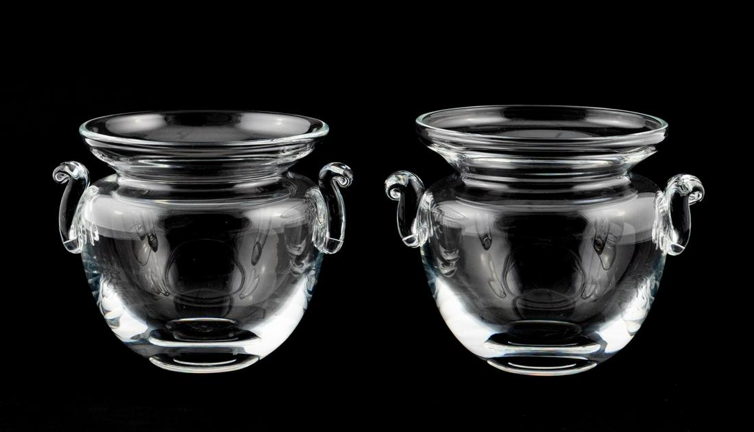 PAIR, STEUBEN CRYSTAL CACHEPOTS BY ERIC HILTON: Eric Hilton for Steuben, design 2003. Pair of urn form cachepot colorless crystal bowls or vases with scroll handles. Etched maker's mark to underside. Approx. h. 6.25", diam. 6.5" (opening).