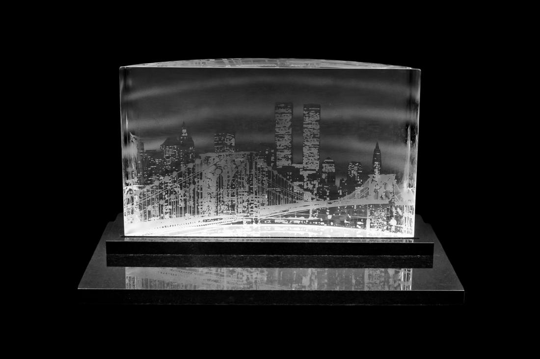 STEUBEN "CITY LIGHTS MANHATTAN" CRYSTAL SCULPTURE: Steuben, design circa 1995. "City Lights Manhattan", an etched crystal sculpture depicting New York city skyline, with the Twin Towers, and raised on a black granite base. Provenance: Acquired from Ne