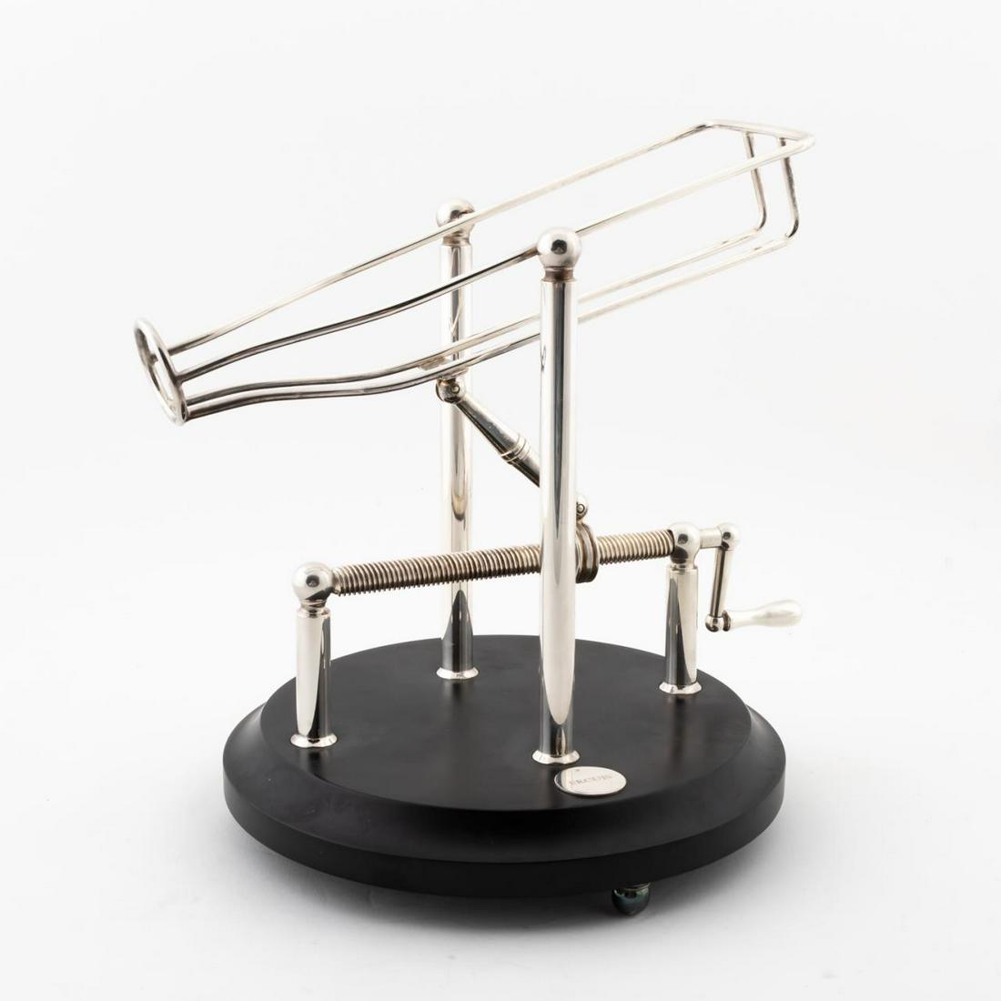 ERCUIS "MANIVELLE" WINE DECANTING MACHINE: Ercuis (French, founded 1867), contemporary. Silver plated wine decanting machine having a crank handle, bottle cradle and circular black wooden base. Marked to the cradle and base. Approx. h. 10.25" 
