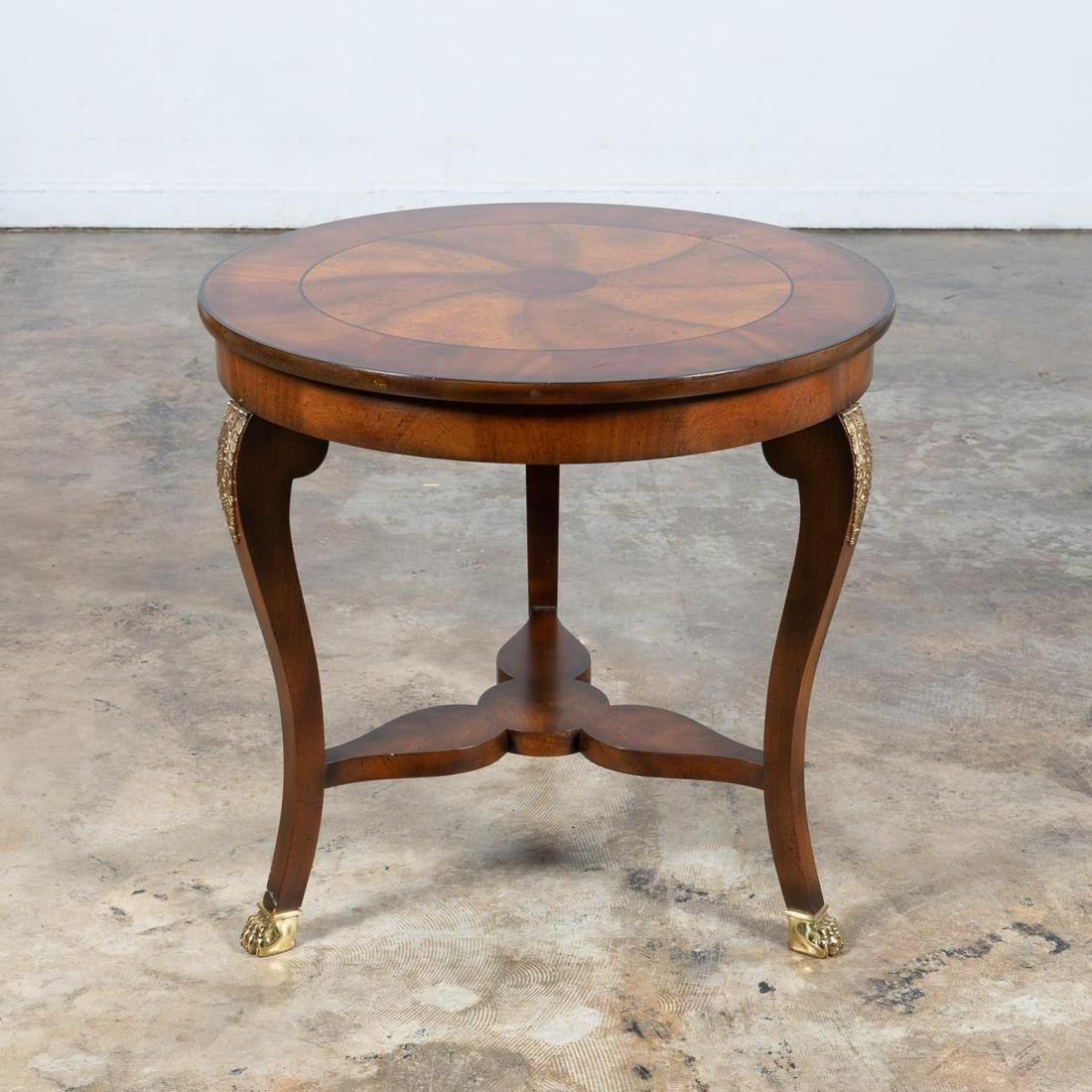 BAKER EMPIRE STYLE INLAY CENTER TABLE: Baker (American), 20th century. Empire style fruitwood and mahogany center table with contrasting veneers creating a pinwheel inlay and having brass ormolu mounts. Maker's plaque to underside. Approx.