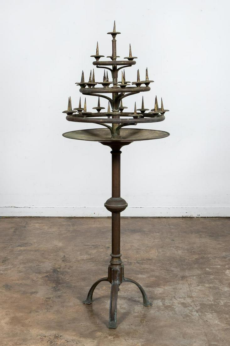 GOTHIC REVIVAL BRASS 3-TIER STANDING CANDLESTANDS: Continental, late 19th to early 20th century. Three-tier brass circular gothic revival ecclesiastical floor candelabra having twenty-eight lights with pickets, rotating body, rolled lid dish and risin