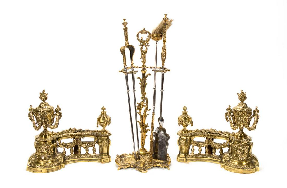 6PC POLISHED BRASS & STEEL FIREPLACE SET: English, 20th Century. Includes a pair of neo-classical chenet with flaming urns, floral swags, and lion's heads as well as three Rococo style fire tools (shovel, broom & tongs) with stand. Apparently