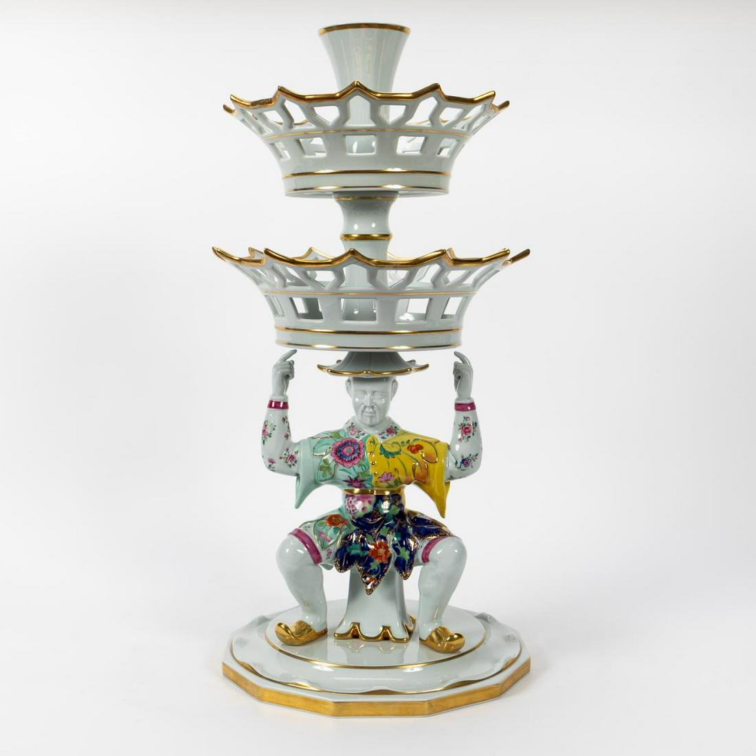 LARGE MOTTAHEDEH "TOBACCO LEAF" FIGURAL EPERGNE: Mottahedeh, contemporary. Large chinoiserie "Tobacco Leaf" porcelain two-tiered epergne with single vase having a gilt accents and two graduated reticulated baskets supported by a male Chinese figure.