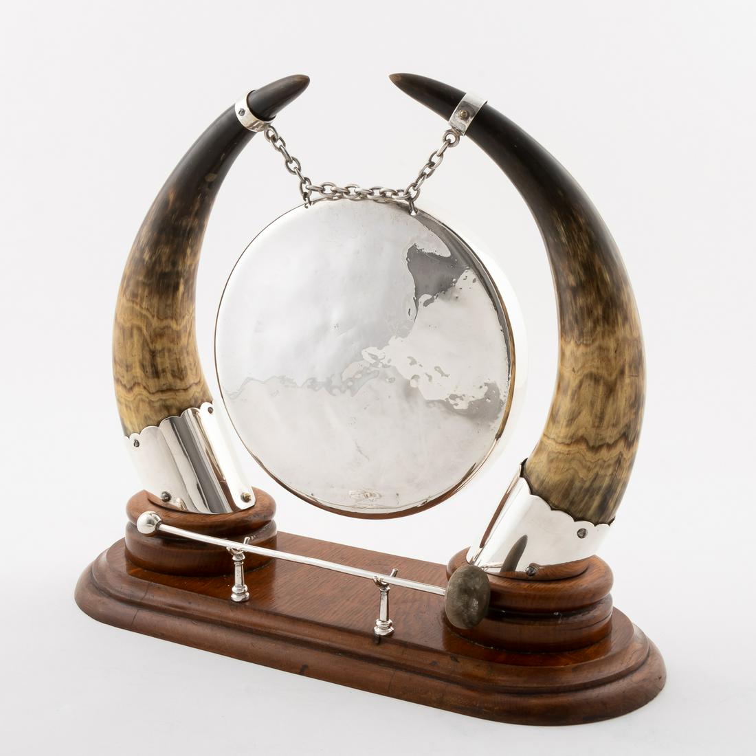 SILVER PLATED MOUNTED HORN DINNER GONG, 2PC: English, late 19th to early 20th century. Victorian or Edwardian era silver plated dinner gong suspended from double natural mounted horns, on an oval oak base with mallet. Unmarked. Approx. h. 13.75"