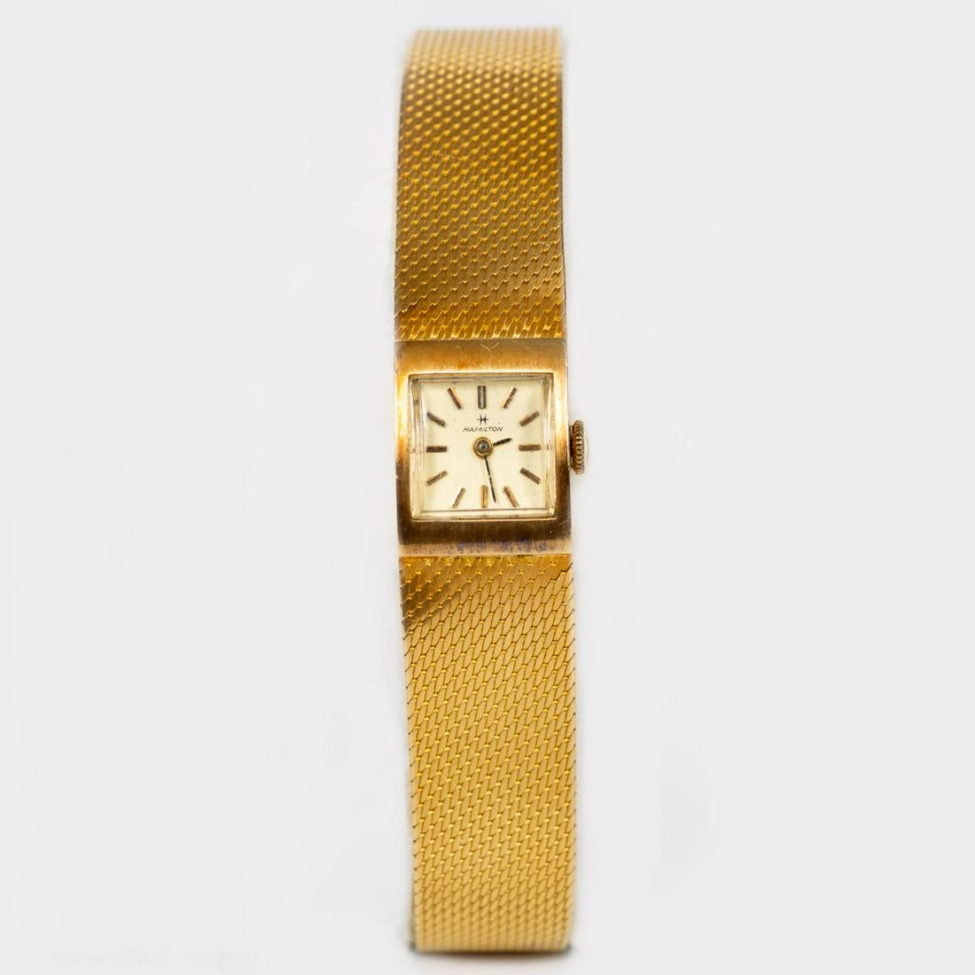 18K YELLOW GOLD, HAMILTON LADIES WRIST WATCH: Hamilton (American, founded 1892). An 18K yellow gold ladies wrist watch with a stick dial, Swiss 17-jewel movement and acrylic crystal. Marked to back of case “88080-8, 70, 18 Ct Gold” and to the