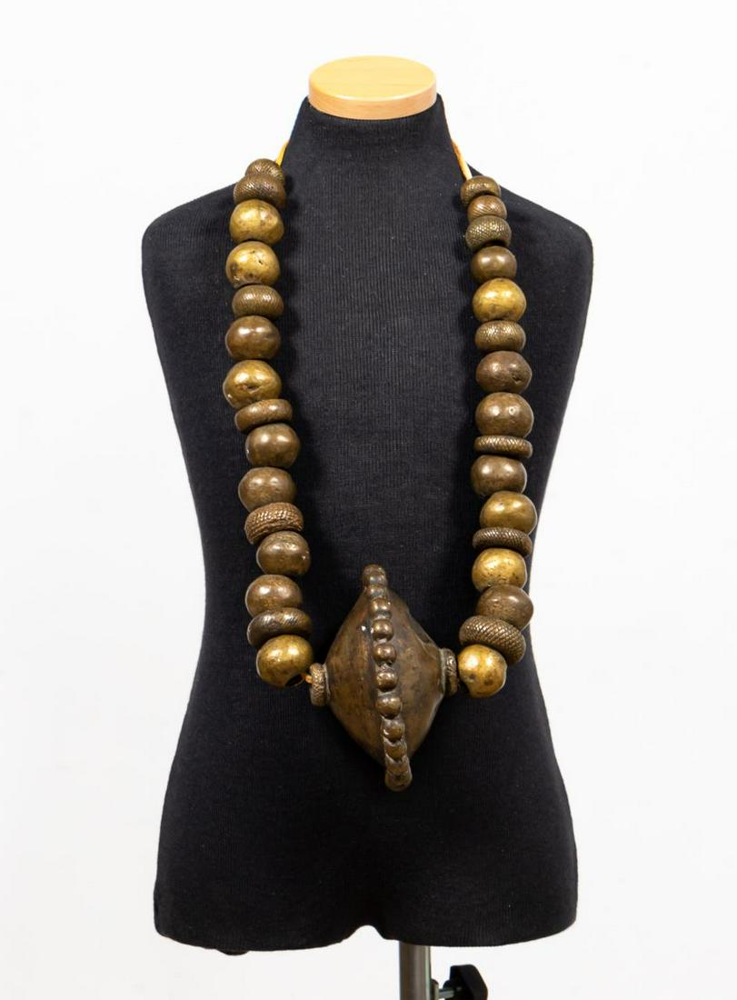 AFRICAN YORUBA BRASS WAIST BEADS ON LEATHER CORD: West African, likely Nigeria - Cameroon, 20th century. Single strand brass beaded necklace with waist beads. Apparently unmarked.Approx. diam. 5" (largest bead), l. 18" (drop lenght).