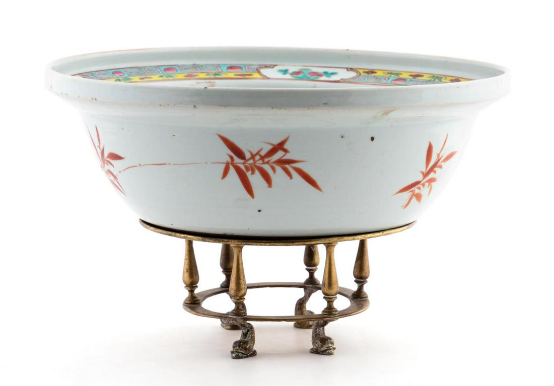 CHINESE EXPORT PRECIOUS OBJECT PORCELAIN WASH BOWL: Chinese. A large export porcelain wash bowl heavily decorated to the interior with precious objects enameling, and red bamboo leaves to exterior; resting on a brass dolphin form base. Apparently unmar