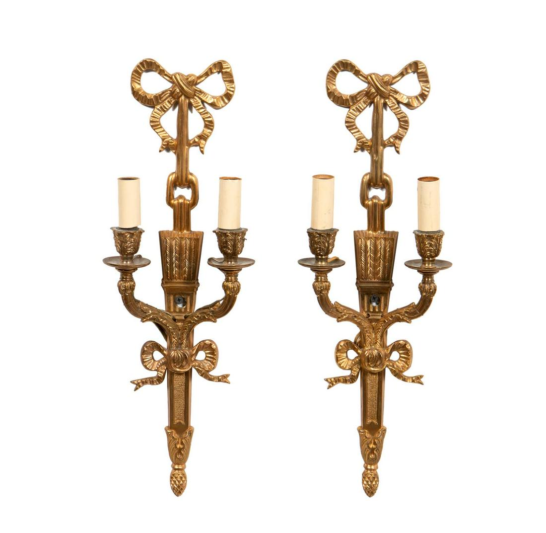 PAIR, TWO LIGHT GILT METAL SCONCES, ELECTRIFIED: Probably French, 20th c., gilt metal sconces with ribbon and foliate decoration, two arms terminating in electrified foliate candle cups.Approx. h. 18" w. 6" d 2.75"