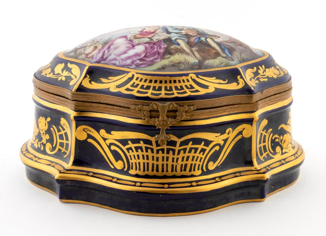 OVERSIZED HAND PAINTED LIMOGES DRESSER BOX: Limoges, 20th century. An oversized cobalt ground dresser box with gilt decorated borders and a figural courting scene to top. Apparently unmarked.Approx: h. 6.5", w. 11.25", d. 8".