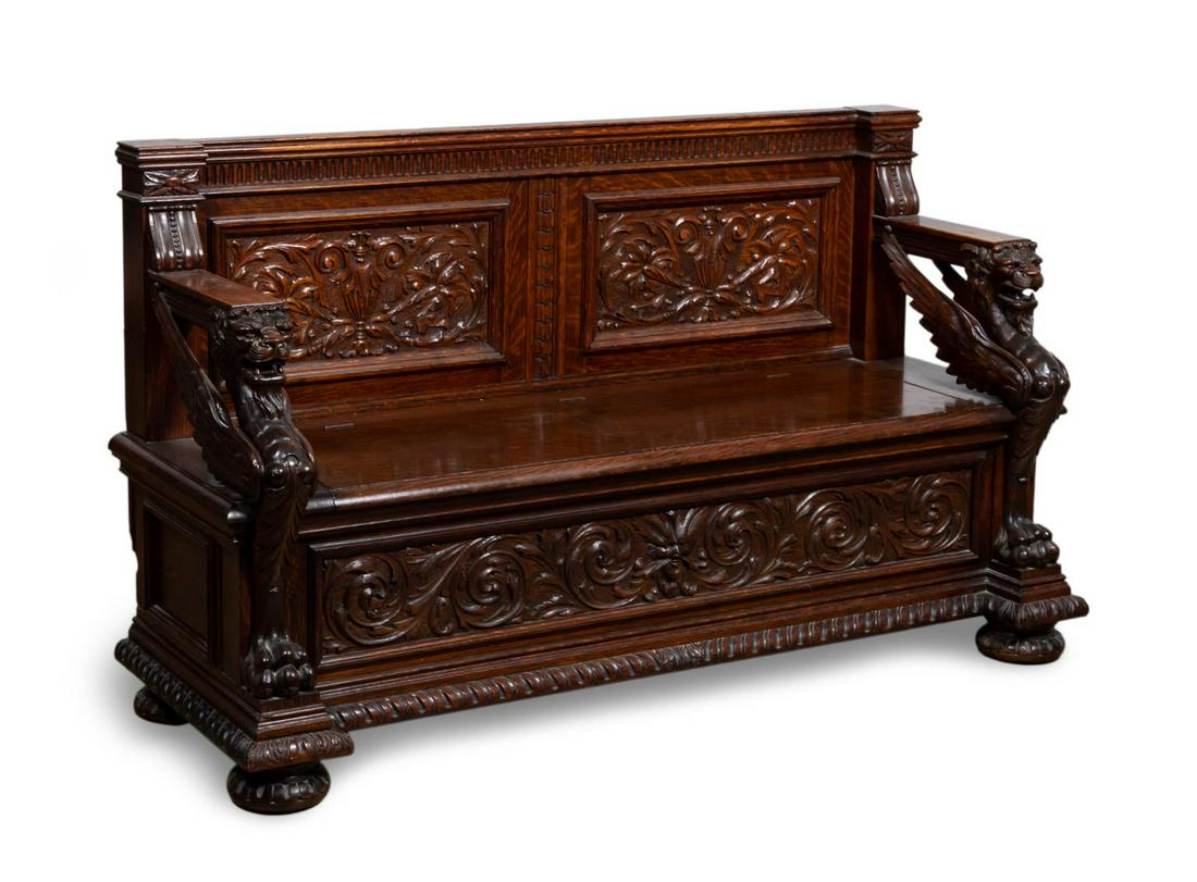 RENAISSANCE REVIVAL HEAVILY CARVED OAK BENCH: American, late 19th century. Renaissance revival carved oak hall bench in the style of R. J. Horner, with winged lion arms, urn and foliate carved panels and flip top seat. Apparently unmarked.Approx.