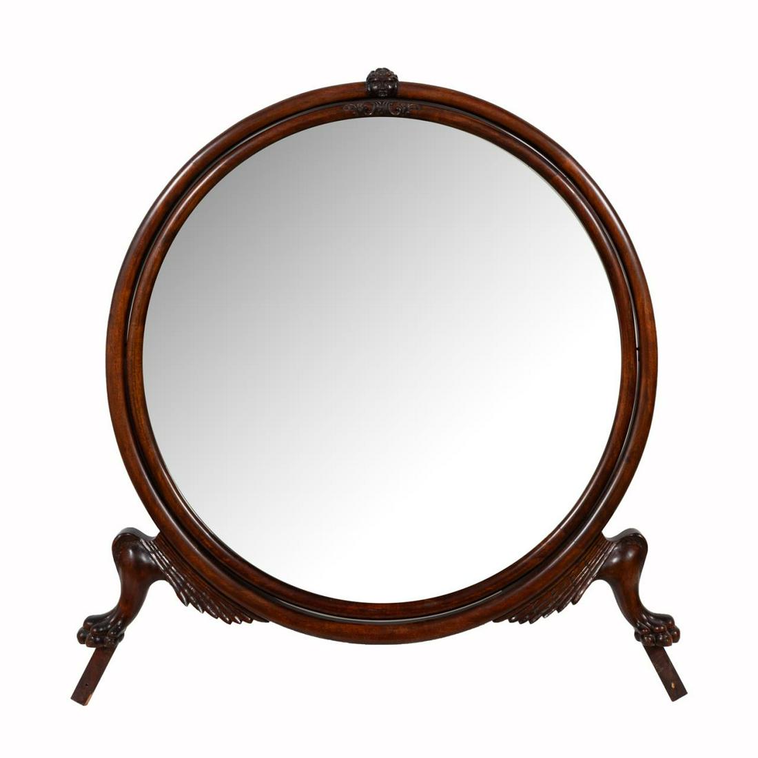 EMPIRE REVIVAL STYLE DRESSER MIRROR ON PAW FEET: American, 20th century. Empire revival style hinged circular dresser mirror with winged paw feet. in a mahogany finish.Approx. h. 49", w. 45.5".