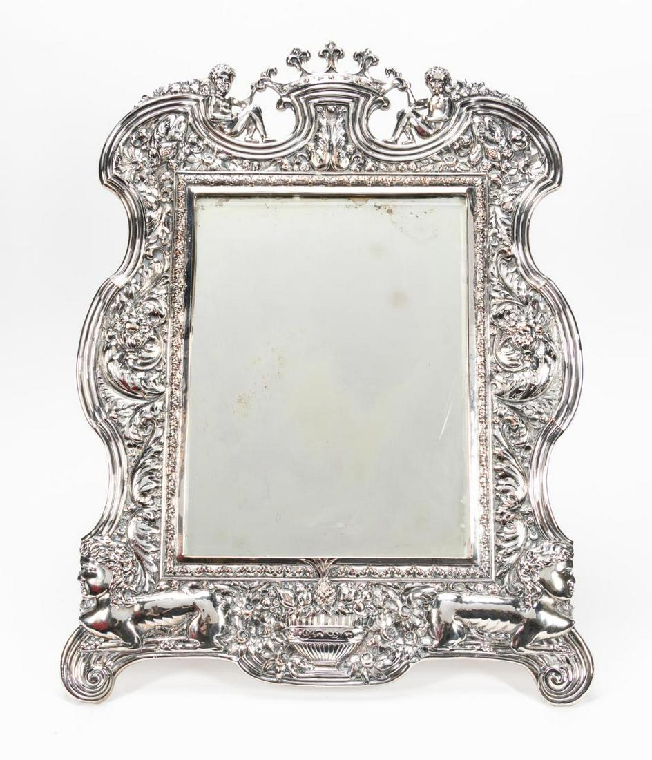 SILVERPLATE ROCOCO REVIVAL REPOUSSE TABLE MIRROR: Likely American, early 20th century. Rococo revival style dressing mirror with ornate repousse decoration. Marked to upper middle on back.Approx. h. 23.25" (laying flat), w. 17.5".
