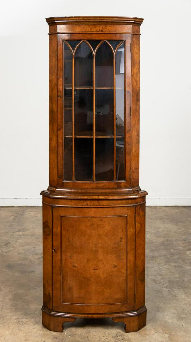 ENGLISH WALNUT BOWFRONT CORNER CABINET: English, 20th century. Small walnut & burled walnut veneer bow-front corner cabinet, the cornice molded top over a conforming single gothic-arch glazed door above a conforming base with single door an