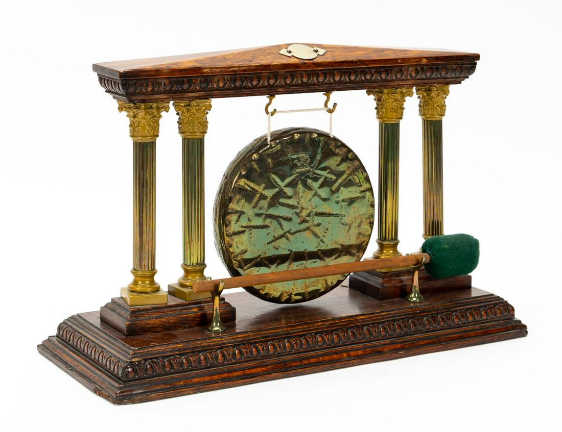 CLASSICAL BRASS AND WOOD DINNER GONG: Probably British, 20th century. Temple-form oak and metal dinner gong with four brass Corinthian columns supporting an entablature form which the gong marked "Burmese" hangs. Includes mallet.Approx. h