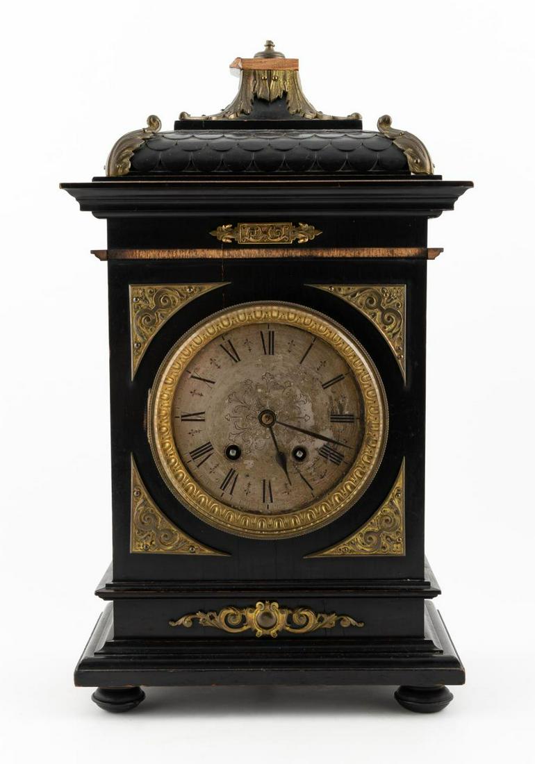 LATE 19TH C. GERMAN BAROQUE TOLE BRACKET CLOCK: German, late 19th Century. Ebonized wood cased Baroque style bracket clock with applied cast brass decorations and bun feet, round engraved brass face with Roman numerals, time and strike spring drive