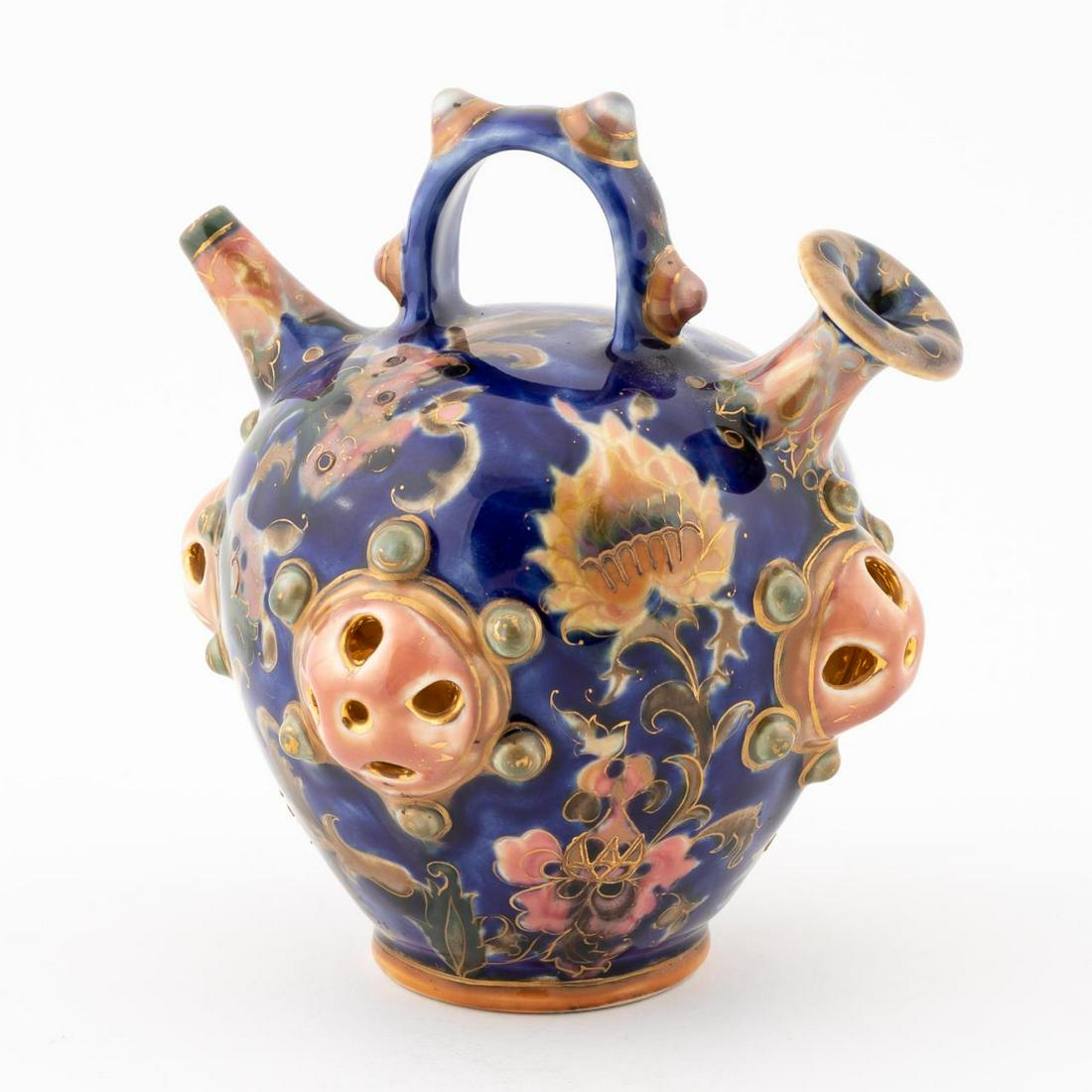 ZSOLNAY PECS HUNGARIAN POTTERY WATER VESSEL: Hungarian, 20th century. A heavily decorated water vessel having foliate forms, handle to top, gilding to each element and a blue ground. Marked "Zsolnay Pecs" to underside.Approx: h. 5.875", w. 5".
