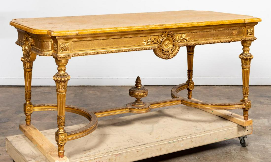LOUIS XVI STYLE MARBLE TOP GILT WOOD SALON TABLE: Continental, late 19th/ early 20th century. Louis XVI style gilt wood salon table with shaped sienna marble top having molded edge on a carved and gilt wood conforming shape base, four turned and tape