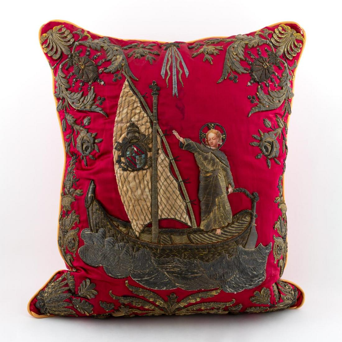 RED METALLIC THREAD EMBROIDERED PILLOW, FIGURAL: Continental. Red satin down pillow with goldwork embroidery and decoupage figure; incorporating scene with an angle steering a small boat at sea and the partial coat of arm of Pope Pius IX on the sail