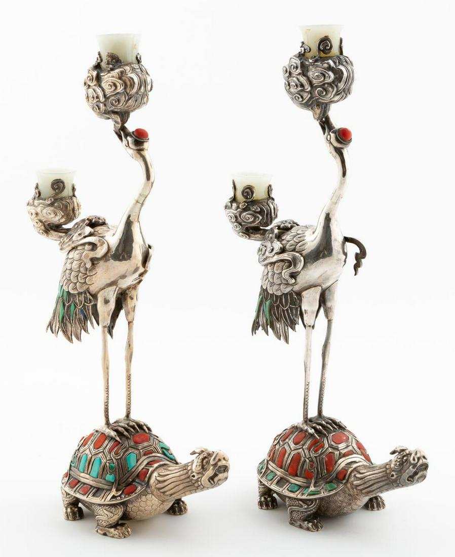 PR. CHINESE SILVER & TURQUOISE CRANE CANDLESTICKS: Chinese. Pair of silver two light candlesticks having a crane on turtle from with inset turquoise and carnelian stones and nephrite wax pans. One faint mark to body. Approx. h. 14.5". w. 3.5", d. 7". 