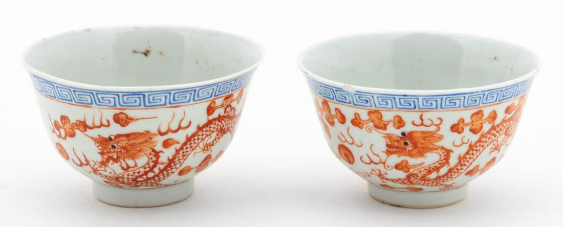 PAIR, CHINESE SMALL PORCELAIN BOWLS WITH DRAGONS: Chinese. Pair of small footed tea or rice bowls, the rims with a blue meandering border and iron-red dragons chasing a pearl below. Four-character mark to the underside. Approx. of one, h. 2", dia. 3.