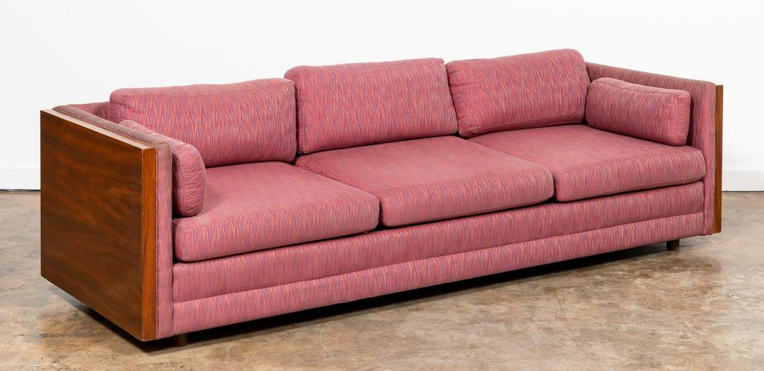 MILO BAUGHMAN WALNUT CASED SOFA, CIRCA 1970: Milo Baughman (American, 1923 - 2003), circa 1970. Three seat Mid-Century Modern upholstered floating couch with walnut veneered sides and magenta upholstery with flame stitch detail. Apparently unmar