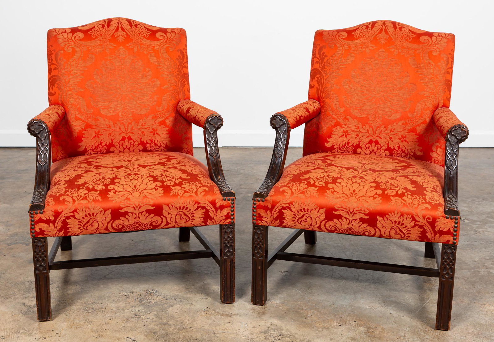 PAIR, CHIPPENDALE STYLE GAINSBOROUGH ARMCHAIRS: American, 20th century. Pair of Gainsborough armchairs in the Georgian Gothic Chippendale taste having red Lee Jofa silk damask, carved mahogany arms and legs, and rising on square front legs. Unmarke