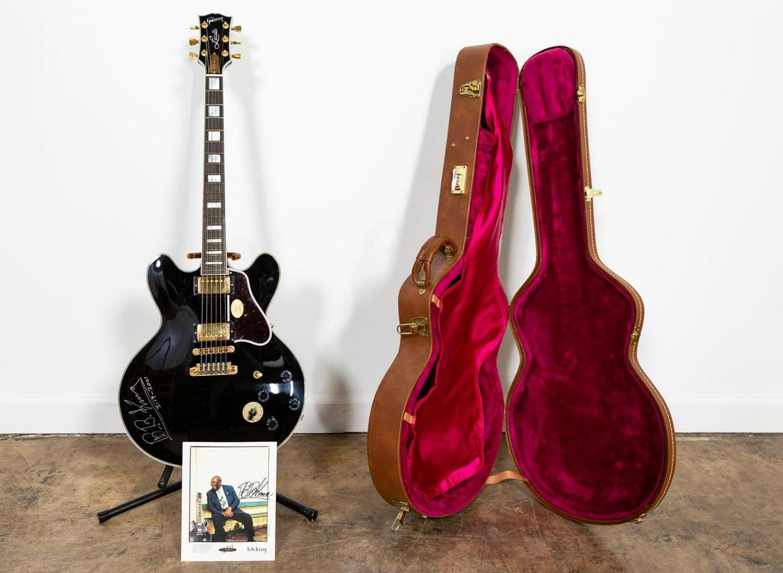 B.B. KING PLAYED "LUCILLE" ELECTRIC GUITAR: Ebony-bodied Gibson B. B. King "Lucille" electric guitar serial number 03550483, with gold hardware and pearloid fret markers, signed on the body "B. B. King / 2-19-2001". In pink lined brown leather 