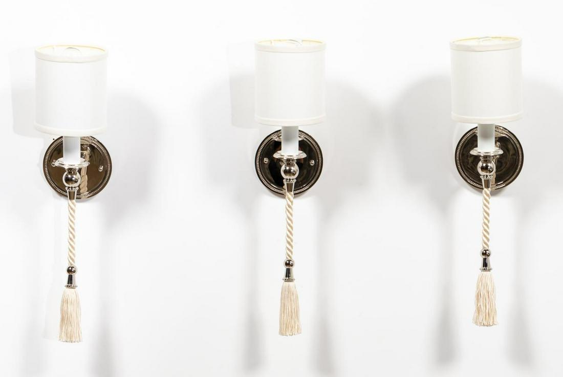 SET, THREE POLISHED NICKEL 'DUCHESS' WALL SCONCES: Boyd Lighting (American, founded 1921), contemporary. Pair of single light polished nickel wall sconces, each having a circular beaded backplate, braided cream cord with tassel, and drum shade. Labels