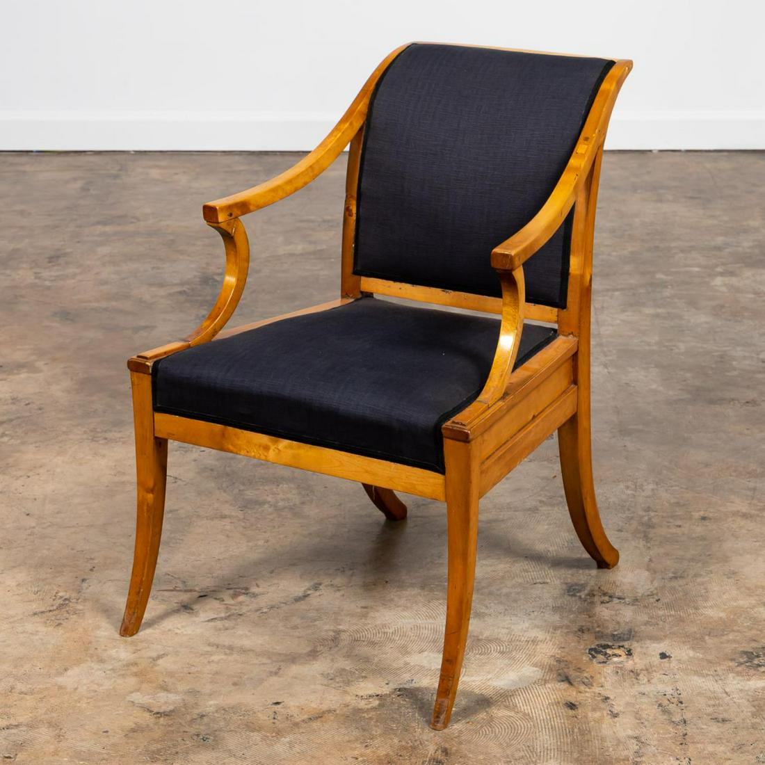 BIEDERMEIER STYLE UPHOLSTERED ARMCHAIR: Continental, likely Swedish, late 19th / early 20th century. Biedermeier style upholstered armchair, likely in birch with saber legs. Apparently unmarked. Approx. h. 32.25", w. 23.5", d. 19.25", seat 