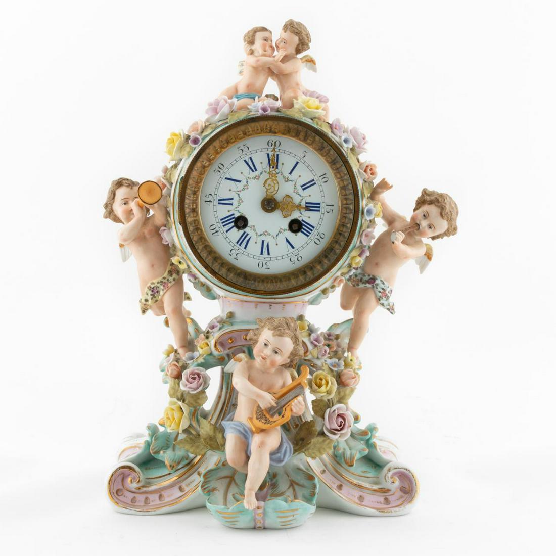 SITZENDORF PORCELAIN CHERUB MOTIF CLOCK: Sitzendorf (German, 1760 - 2012), late 19th / early 20th century. Cherub motif porcelain rococo style clock with floral and musical motif. Crossed lines to underside. Approx. h,. 13.5", w. 8.5".