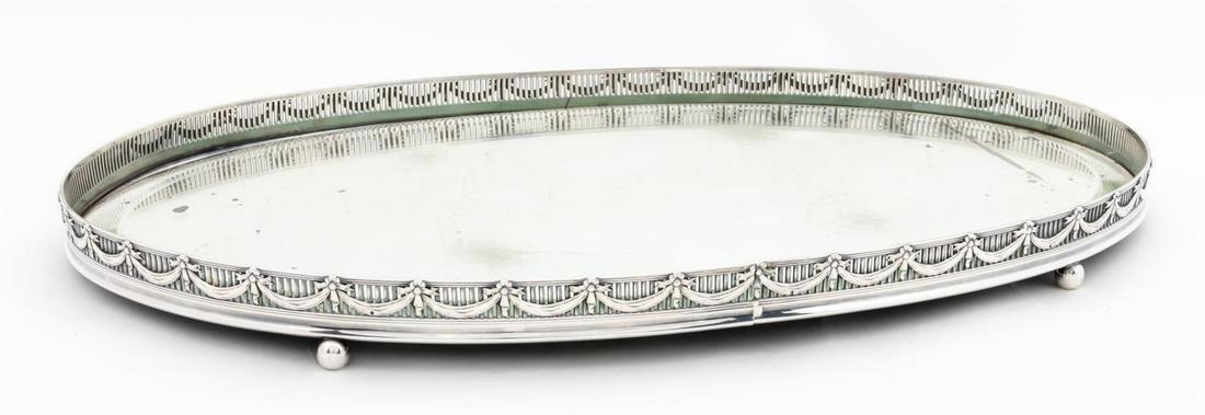 SILVERPLATE OVAL MIRRORED DINING TABLE PLATEAU: Continental, probably French, early 20th century. Oval mirrored silverplate centerpiece plateau, pierced gallery with swags and bows on ball feet, beveled mirror. Apparently unmarked. Approx. h. 1", w