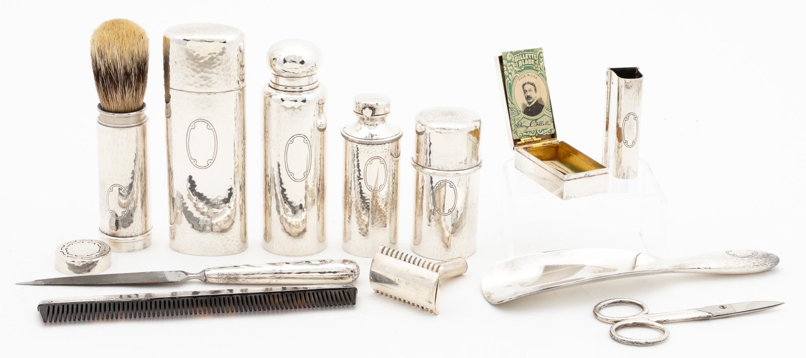 TIFFANY STERLING SILVER TOILETRY SET, LEATHER CASE: Tiffany and Company, 20th century. Leather cased hammered sterling travel set comprising comb, toothbrush cover, scissors, razor case with razor, shoe horn, nail file, cylindrical shaving brush case, 