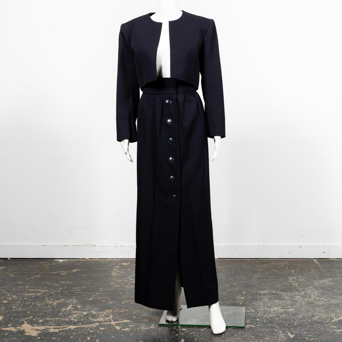 2PC YVES ST. LAURENT NAVY SKIRT & JACKET ENSEMBLE: Yves Saint Laurent, couture (French, founded 1961), 1980/90s. Two navy blue wool ensemble comprising a bolero style jacket with circular neckline and long sleeves. The pleated skirt with front hook an