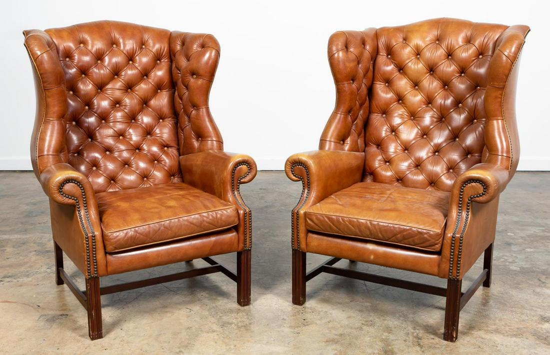 PR, GEORGIAN STYLE TUFTED LEATHER WINGBACK CHAIRS: American, 20th century. Pair of brown tufted leather wing chairs in the Georgian Chippendale taste, having a loose seat cushion and rising on square legs with stretchers. Upholsterer's tag to the unde
