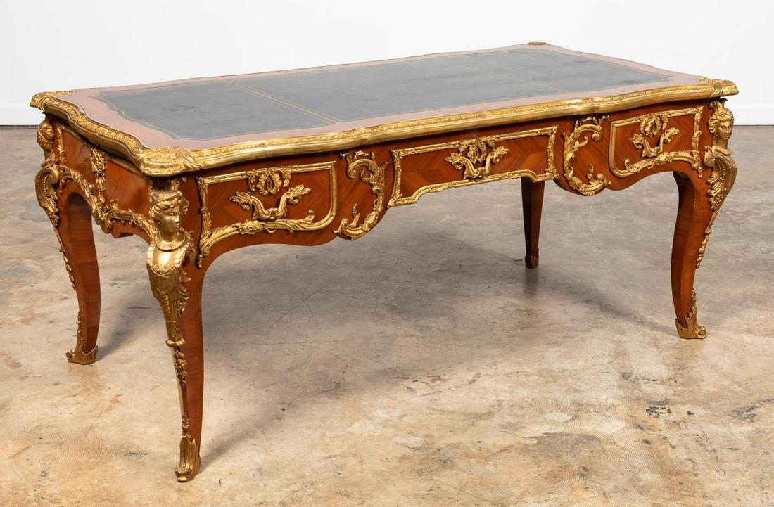 FRENCH REGENCE STYLE ORMOLU MOUNTED BUREAU PLAT: French, 20th century. Marquetry bureau plat or desk in the Regence/Louis XV taste having a leather writing surface, figural bronze ormolu mounts, three drawers and rising on cabriolet legs. Unmarked. 