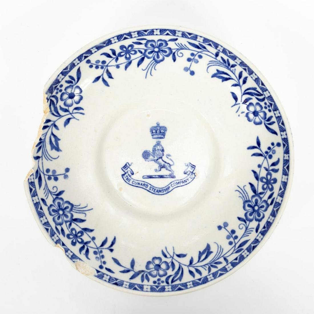 RMS CARPATHIA, SALVAGED FIRST CLASS PARTIAL SAUCER: RMS Carpathia, Cunard Line, maiden voyage May 5, 1903; sunk July 15, 1918. Salvaged first class Mintons 'Ormond' pattern blue and white floral partial pottery saucer with Cunard Line logo. Stamped to 