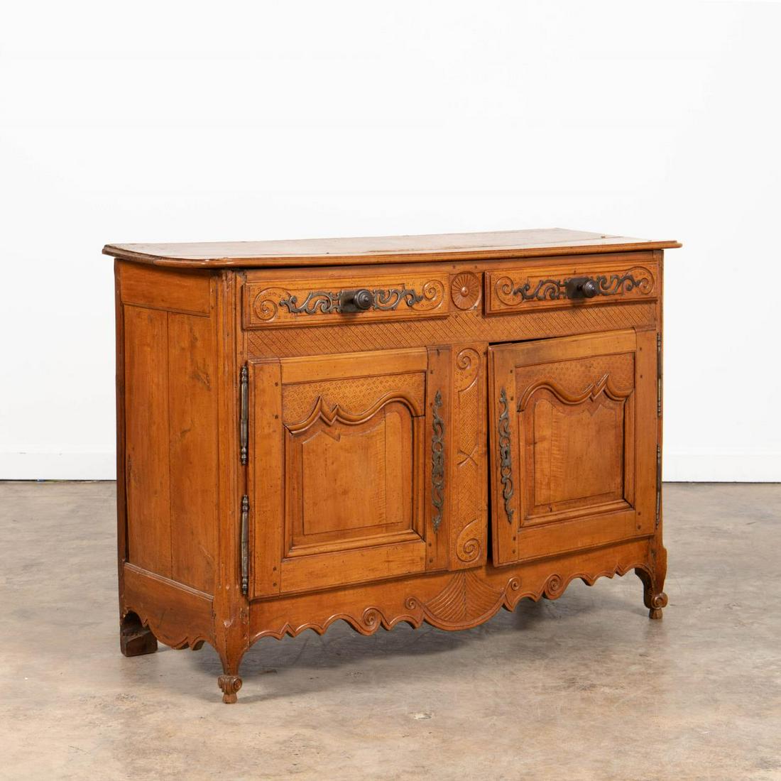 18TH C. FRENCH LOUIS XV PROVINCIAL BUFFET: French, 18th century. Provincial Louis XV carved cherry or fruitwood buffet having two drawers above double paneled doors with patterned ground, scalloped fan carved apron and rising on front cabriole