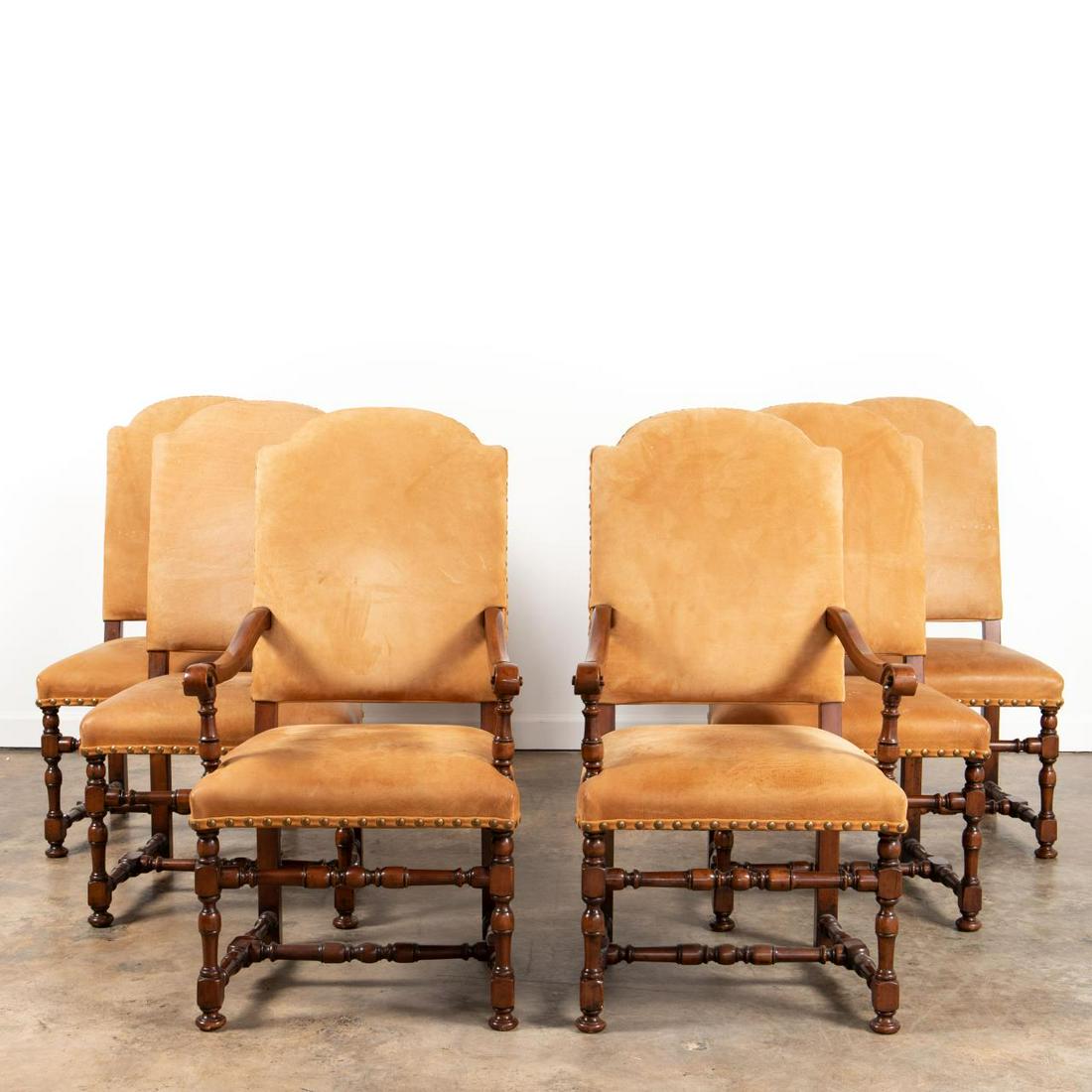 SET, SIX TAN LEATHER BAROQUE STYLE DINING CHAIRS: Possibly Continental, late 20th century. Set of two arm and four side dining chairs in the baroque taste having tan leather upholstery, brass nailhead trim, and rising on turned dark stained wooden le