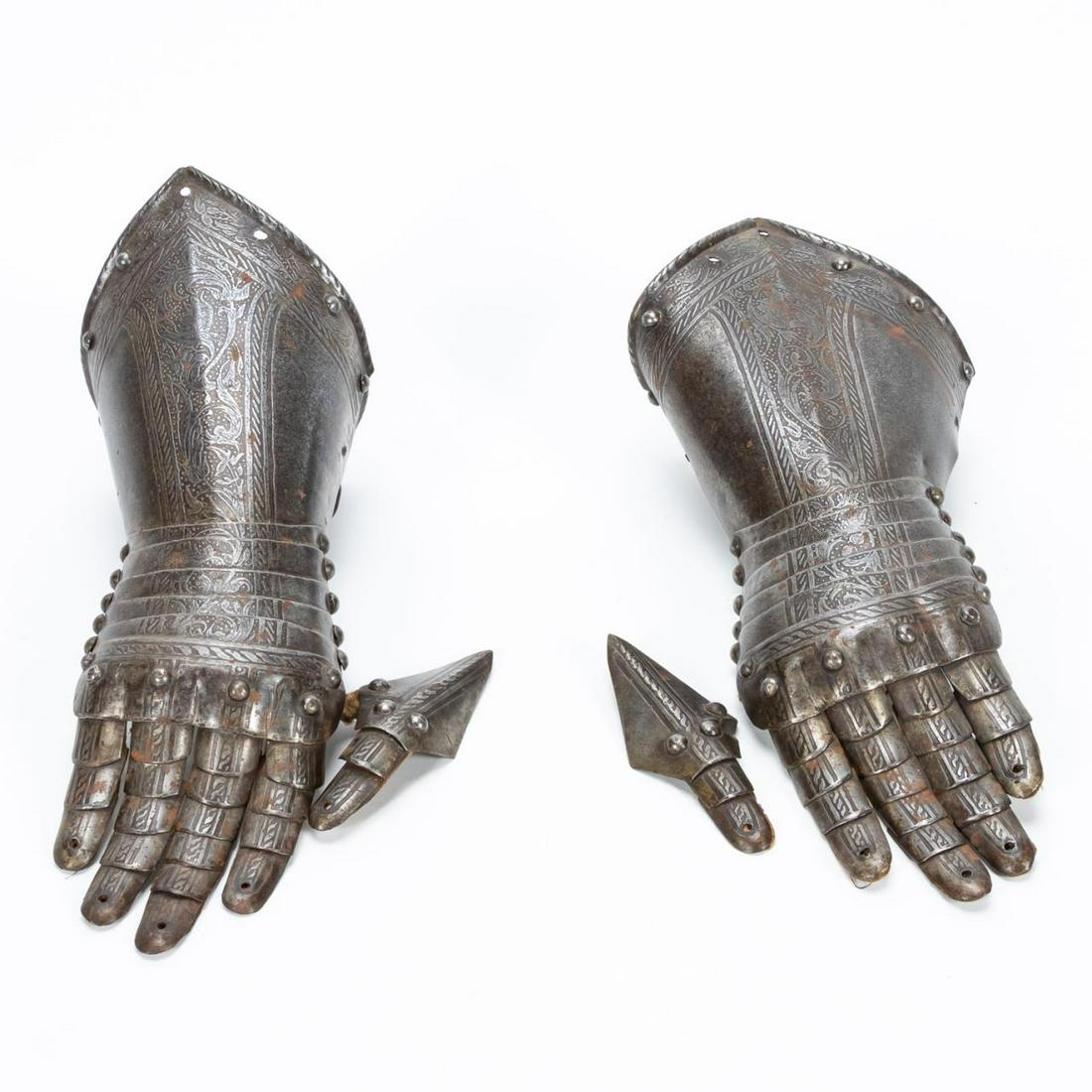 PAIR OF 17TH C. ITALIAN ENGRAVED STEEL GAUNTLETS: Italian, first quarter 19th century. Pair of steel gauntlets from a suit of armor, each engraved with scrolled foliate and fantasy figural detail, having pointed and flared cuffs, five articulated met