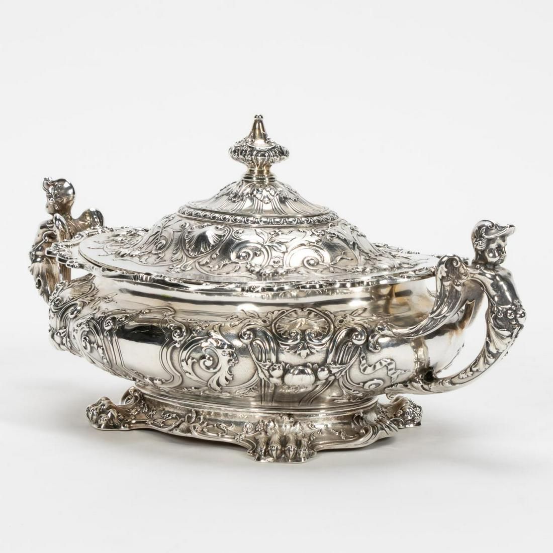 GORHAM STERLING LIDDED TUREEN, PUTTI HANDLES: Gorham (American), circa 1915. Ornate sterling silver covered vegetable dish having putti handles, center cartouche, and paw feet. Appropriately marked to underside. Museum / Historical society deacce