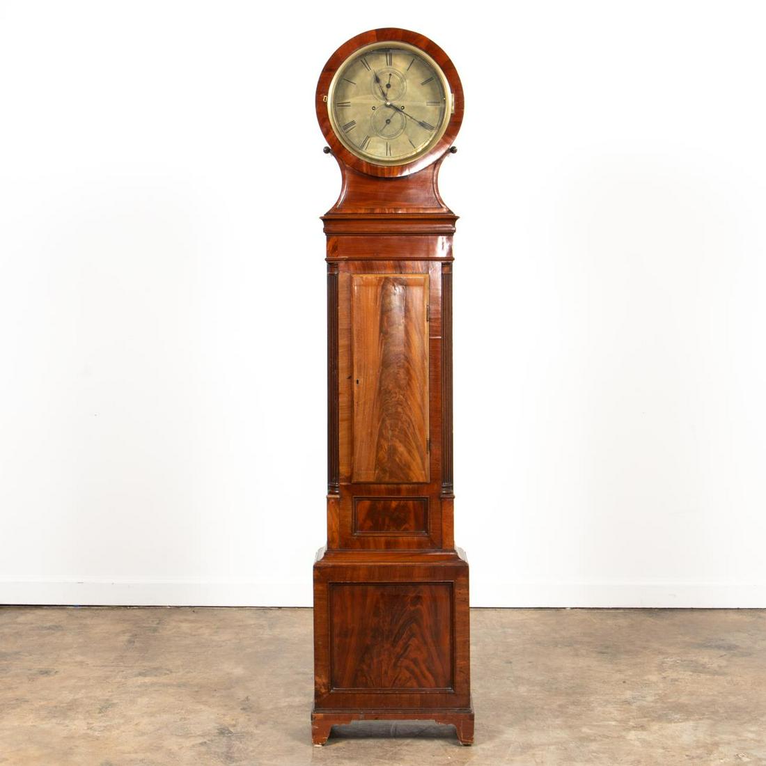 19TH C. SCOTTISH MAHOGANY TALL CASE CLOCK: Andrew Millar (Scottish, active 1827-1903), second quarter 19th century. Mahogany round top tall case, having a brass face with Roman numerals, second and date hands, tapering trunk, and rising on bra